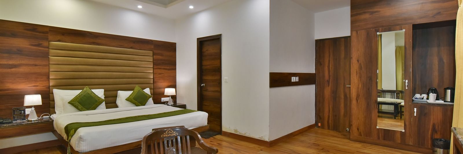 A large bed placed in front of two sofas at the Luxury Room Without Balcony at DLS Highland Resort and Spa, Mussoorie.